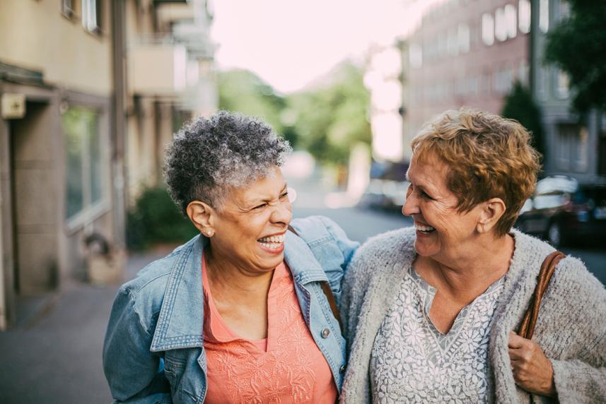 Two women laughing together, walking outside